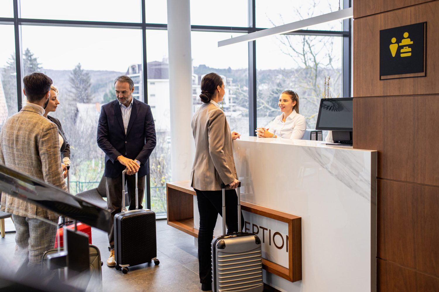 Group of business people arriving in a hotel for a business conference, checking in at the reception.